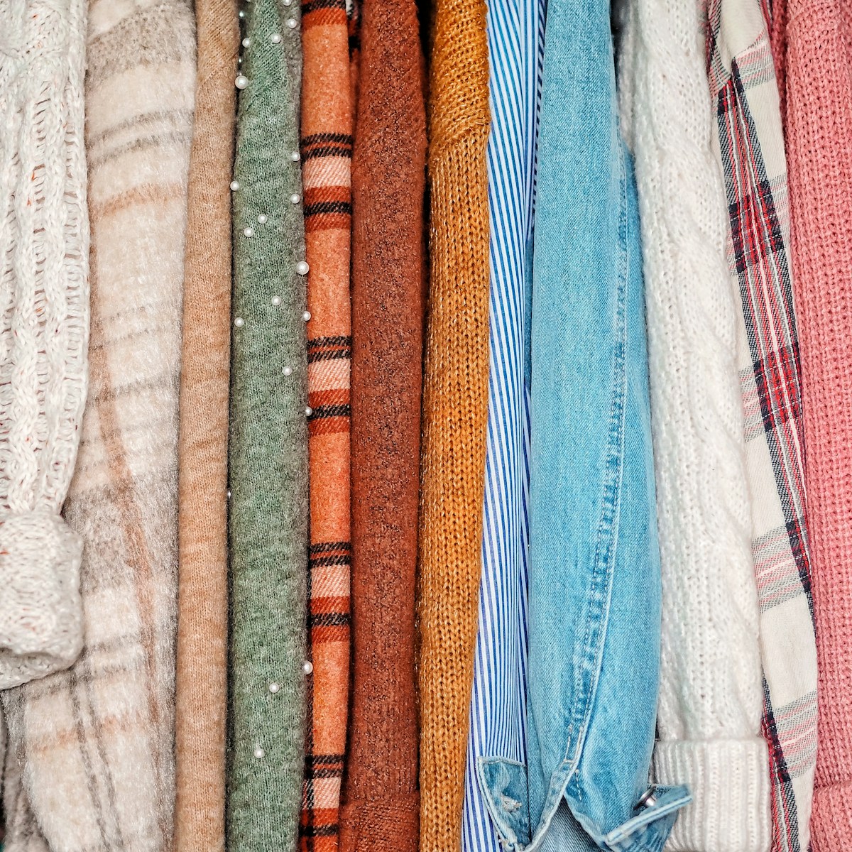 a rack of sweaters and scarves hanging on a wall